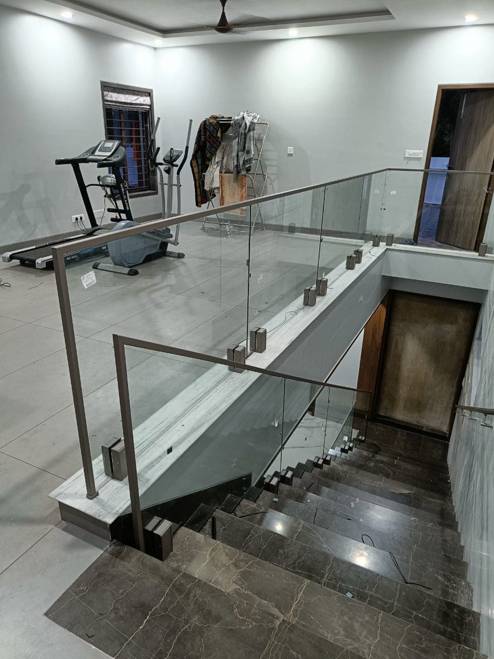 Glass railing with metal fittings along a staircase opening