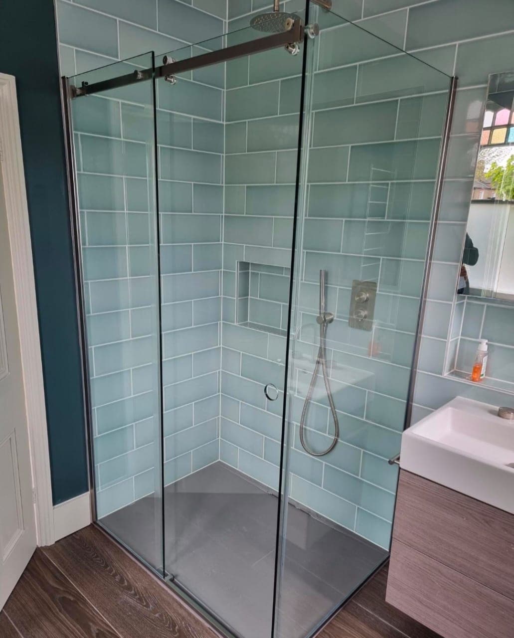 Glass shower enclosure with a sliding door in a tiled bathroom